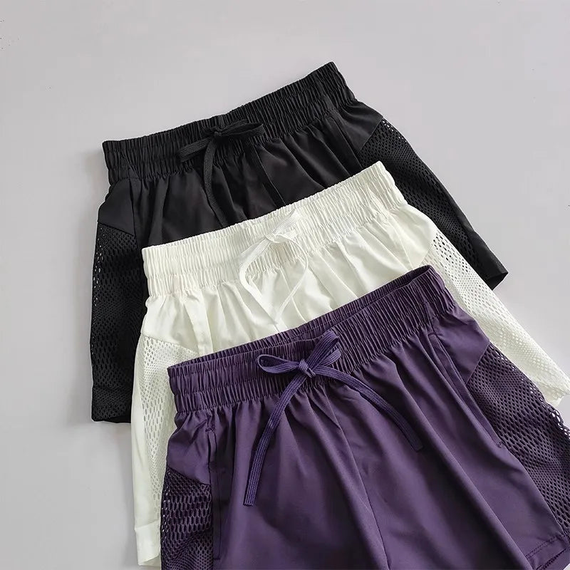 Three pairs of breathable gym shorts for women in black, white, and purple with mesh details