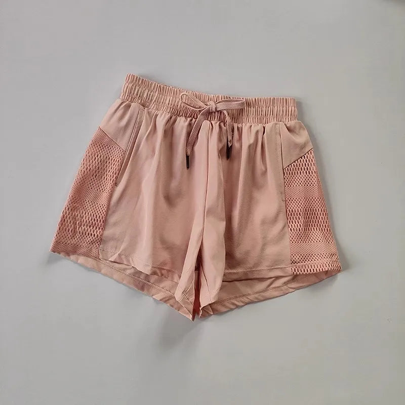 Light pink breathable gym shorts for women featuring mesh panels for enhanced airflow