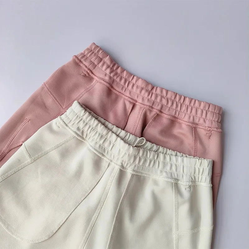 Two pairs of Casual Sports Shorts for Women in pink and cream colors featuring elastic waistbands.