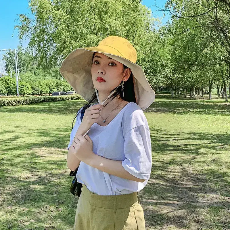 Woman wearing a stylish UPF 50 sun protection hat outdoors in a shaded park area