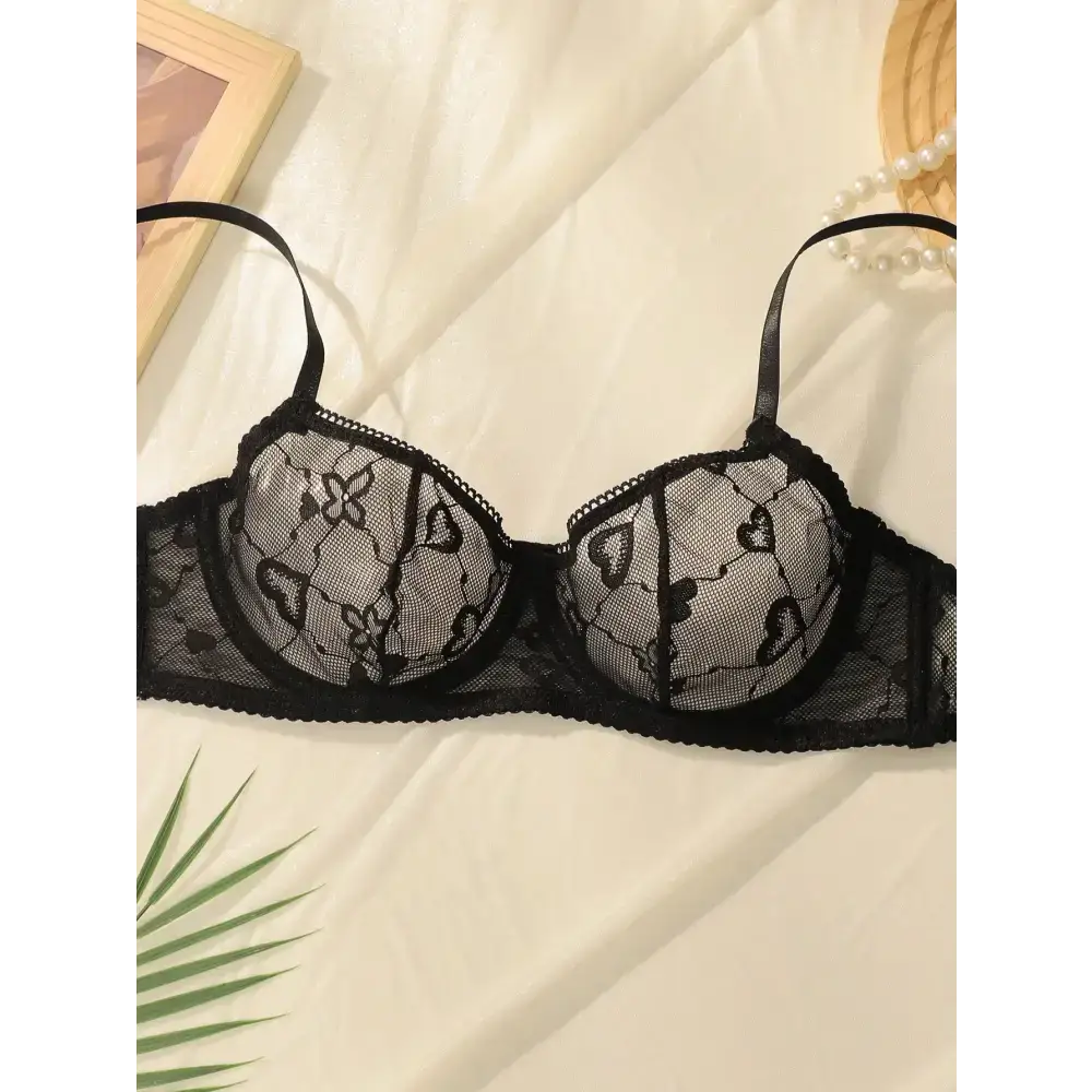 Black delicate sexy lace lingerie set bra with heart and floral patterns on white fabric background
