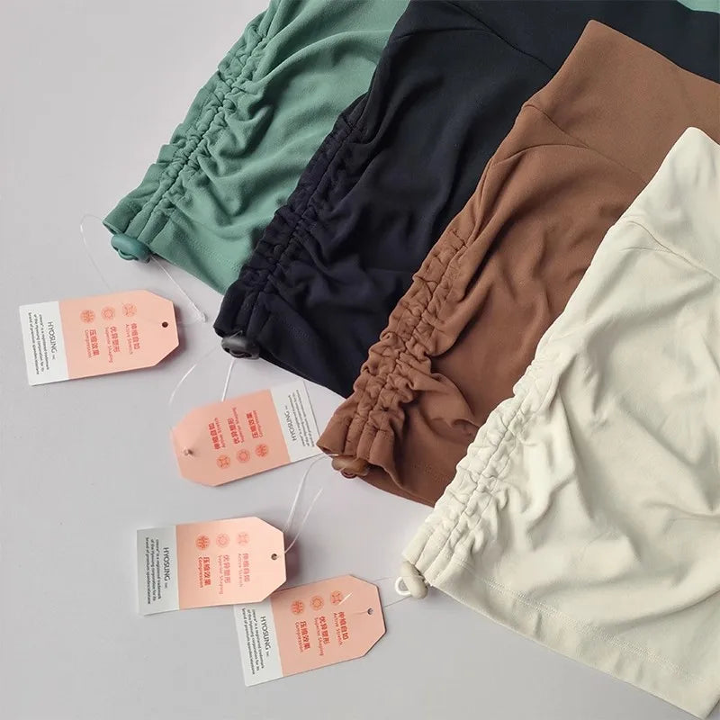 Assorted drawstring sports shorts for women in green, brown, and cream colors with hang tags